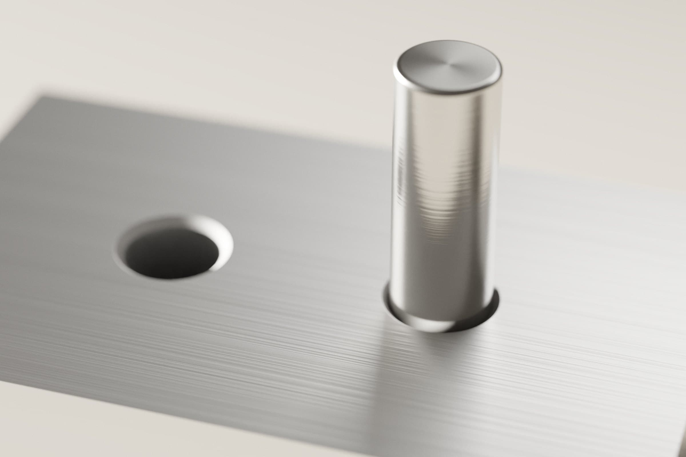 Stahlstift in der Bohrung eines Blocks aus gebürstetem Aluminium, daneben eine leere Bohrung